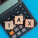 tax-planning-concept-with-wooden-cubes-calculator-blue-table-flat-lay (1) - Pratama Institute natura
