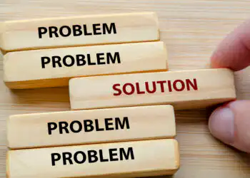 Blocks spell 'PROBLEM' with one 'SOLUTION' block being pulled out, illustrating finding a solution to a problem.