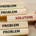 Blocks spell 'PROBLEM' with one 'SOLUTION' block being pulled out, illustrating finding a solution to a problem.