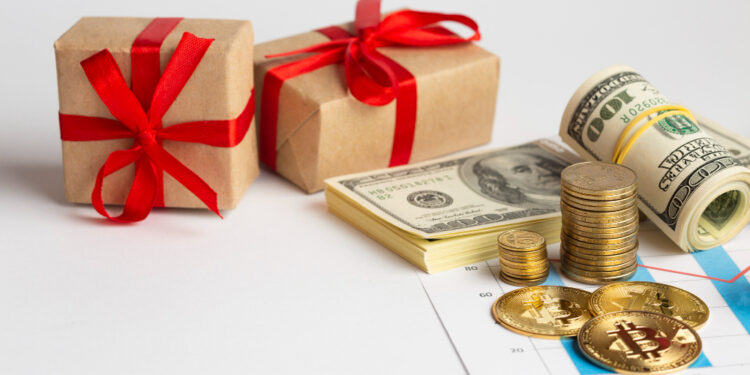 Two gift boxes with red ribbons beside rolled cash, coins, and a financial chart.