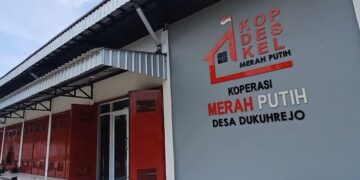 Exterior of a cooperative building with red doors and a large sign reading Koperasi Merah Putih Desa Dukuhrejo