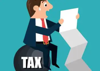 Cartoon businessman perched on a large bomb labeled 'TAX' while reading a document, symbolizing a tax burden stress test.