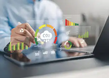 Hands over a tablet with floating CO2 analytics: charts and icons about emissions and sustainability.